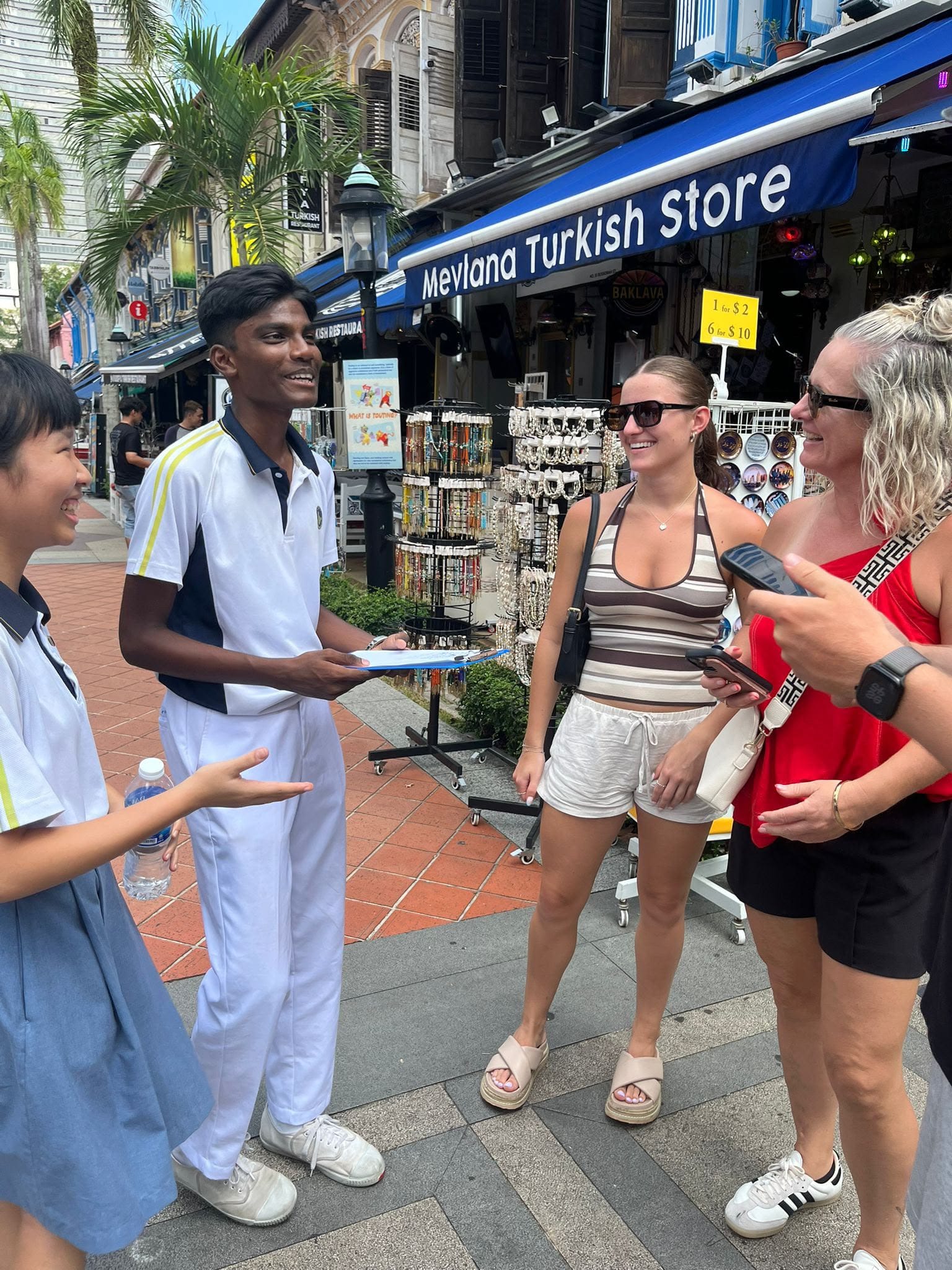 Two students talking to two tourists in front of a store